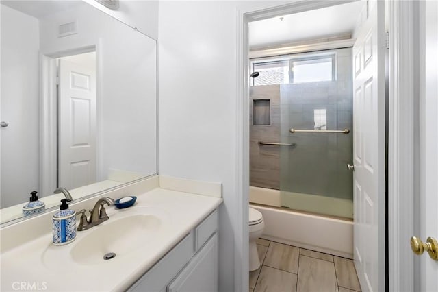 bathroom with visible vents, vanity, toilet, and enclosed tub / shower combo