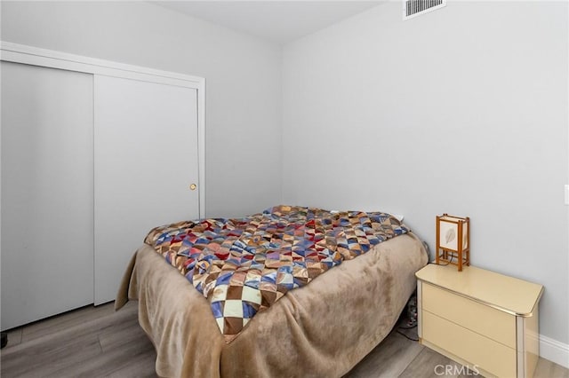 bedroom featuring a closet, visible vents, and wood finished floors