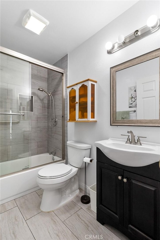 bathroom featuring toilet, combined bath / shower with glass door, and vanity