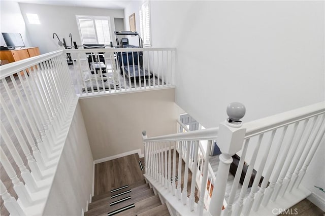 staircase featuring wood finished floors and baseboards