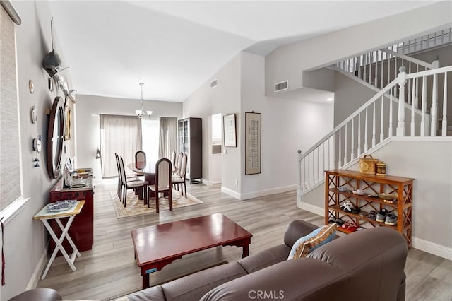 living area with baseboards, visible vents, stairway, vaulted ceiling, and light wood-type flooring