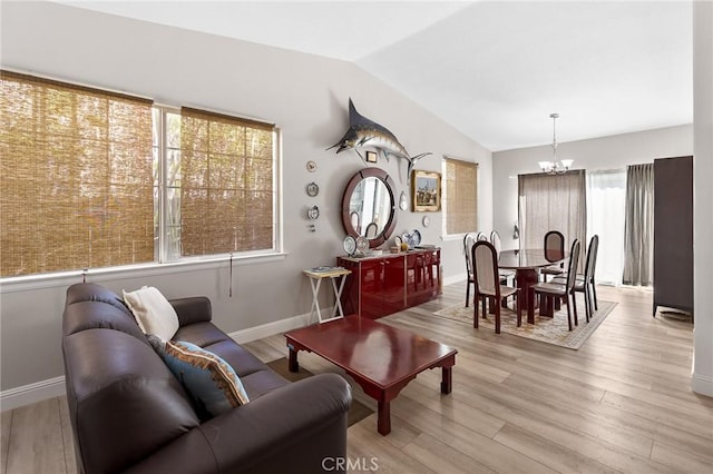 living room with lofted ceiling, baseboards, a notable chandelier, and light wood-style floors