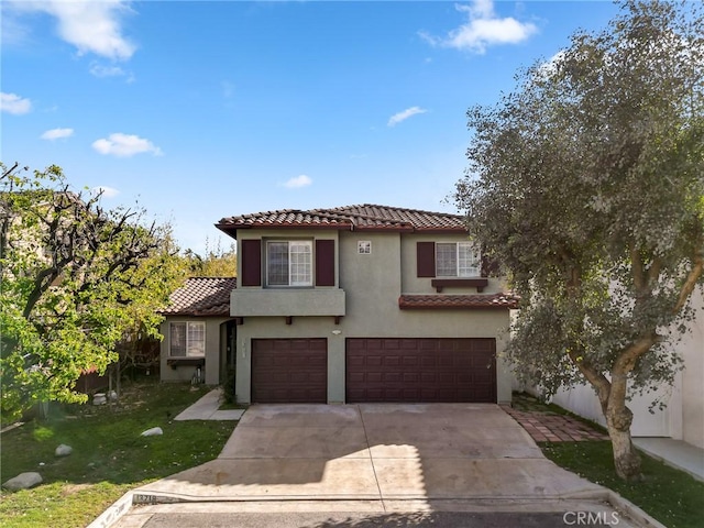 mediterranean / spanish-style home featuring concrete driveway, a tiled roof, an attached garage, a front lawn, and stucco siding