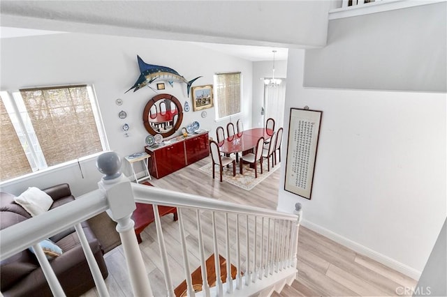 staircase featuring an inviting chandelier, baseboards, and wood finished floors