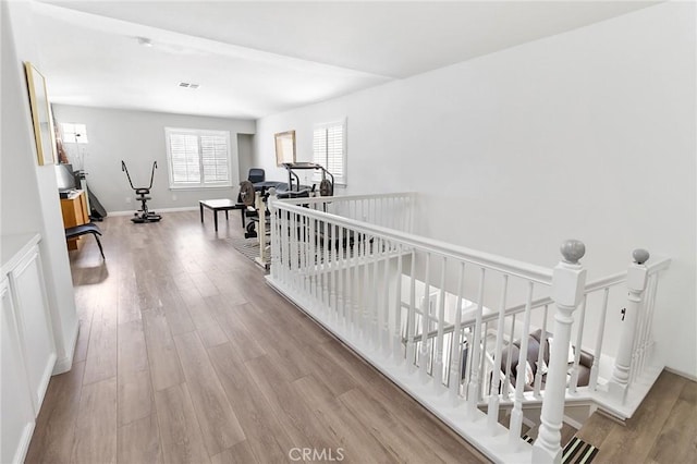 corridor featuring an upstairs landing, baseboards, and wood finished floors