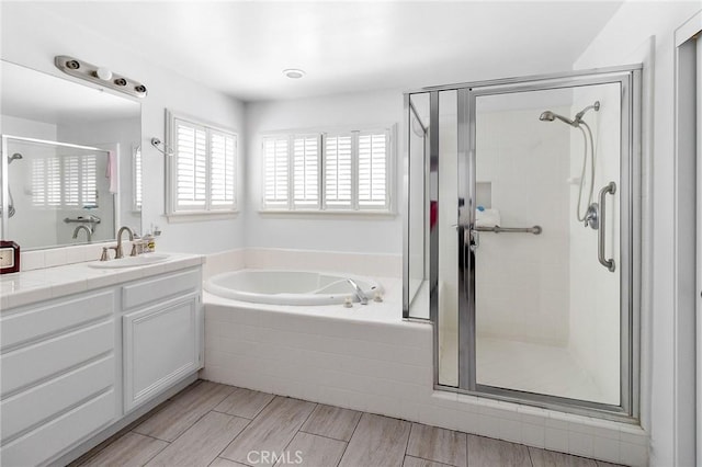 full bathroom featuring vanity, a shower stall, a bath, and wood tiled floor