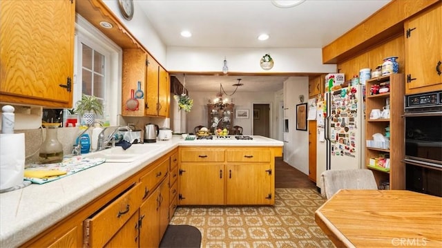 kitchen with light countertops, white appliances, a peninsula, and a sink