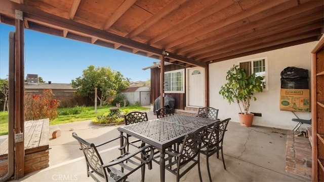 view of patio featuring outdoor dining area, fence, and an outdoor structure