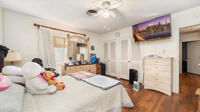 bedroom with a textured ceiling, wood finished floors, visible vents, and a ceiling fan