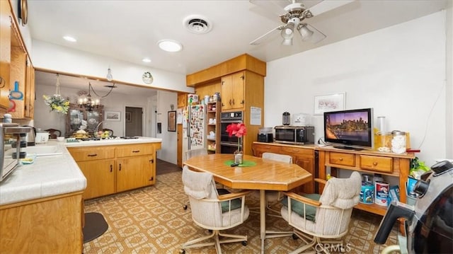 kitchen with ceiling fan with notable chandelier, a sink, visible vents, light floors, and stainless steel microwave