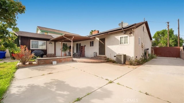 view of front of house featuring entry steps, central AC, a gate, roof mounted solar panels, and stucco siding