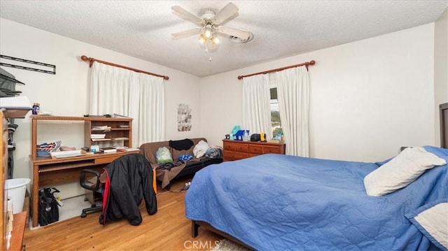 bedroom with ceiling fan, a textured ceiling, and wood finished floors