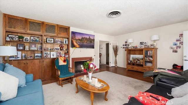 living area with a fireplace, visible vents, and a textured ceiling