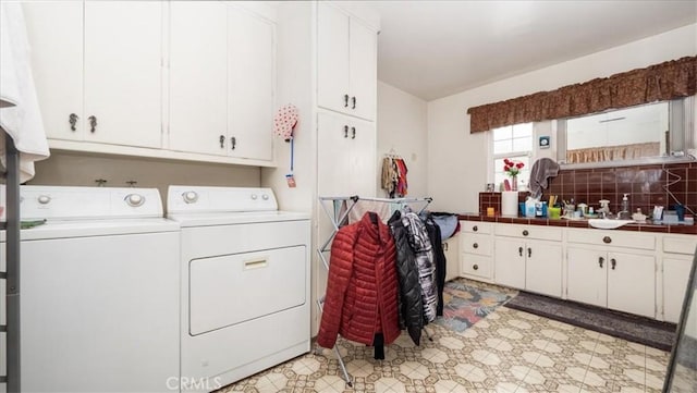 laundry area with washer and dryer, cabinet space, a sink, and light floors