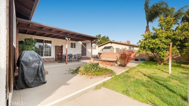 back of property featuring a patio area, a lawn, fence, and stucco siding