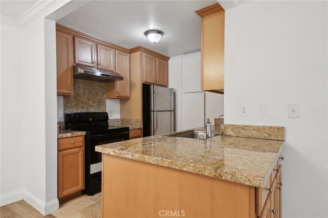 kitchen with black range with electric stovetop, freestanding refrigerator, a sink, a peninsula, and under cabinet range hood