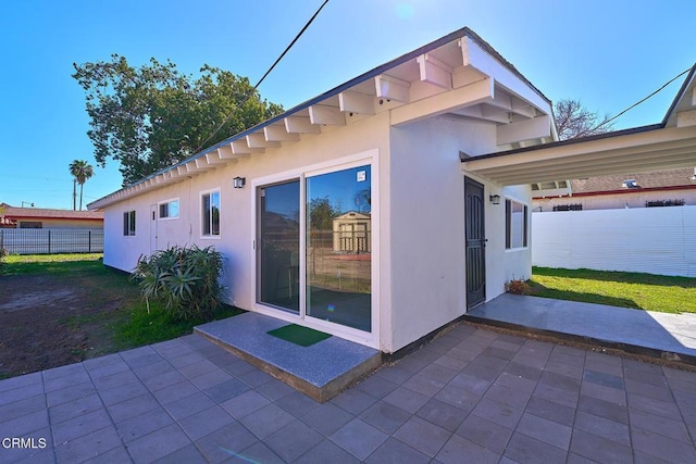 view of home's exterior with fence, a patio, and stucco siding