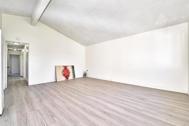 spare room with light wood-style flooring, baseboards, lofted ceiling with beams, and a textured ceiling