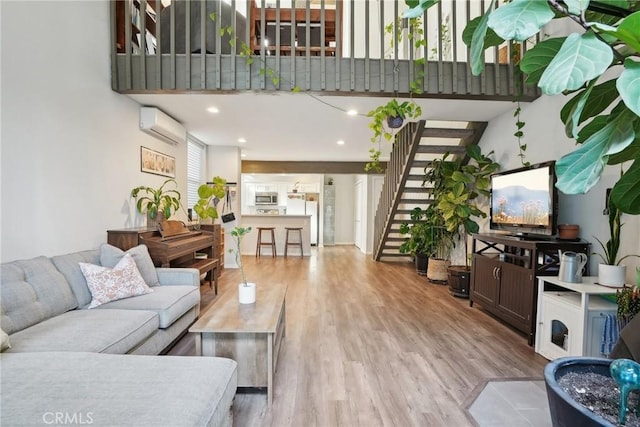 living area featuring stairway, a wall unit AC, a towering ceiling, and wood finished floors