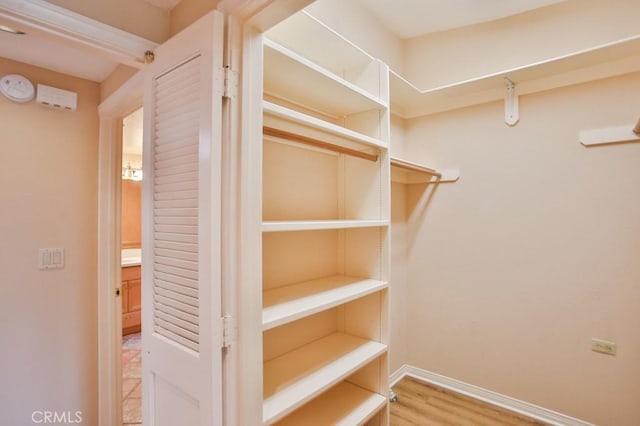 walk in closet with wood finished floors