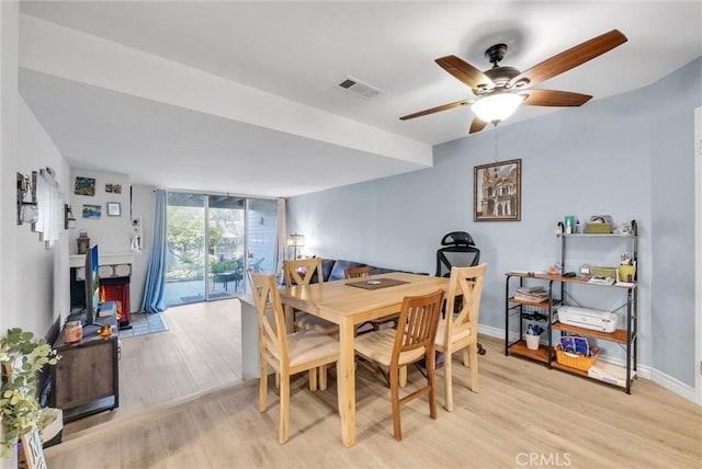 dining area featuring light wood-type flooring, visible vents, baseboards, and floor to ceiling windows