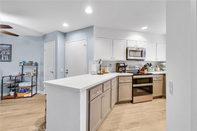 kitchen featuring light wood finished floors, light countertops, decorative backsplash, a peninsula, and stainless steel appliances