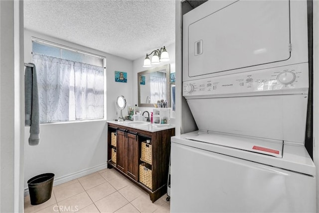 bathroom featuring a textured ceiling, stacked washer and dryer, vanity, and tile patterned flooring