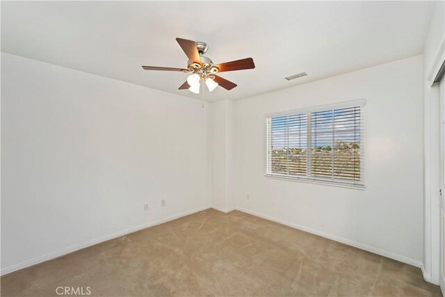 empty room with visible vents, light colored carpet, baseboards, and a ceiling fan