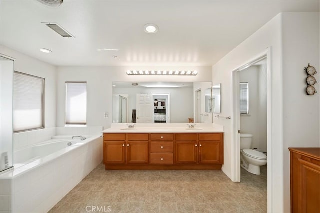 bathroom featuring visible vents, double vanity, a sink, a garden tub, and toilet