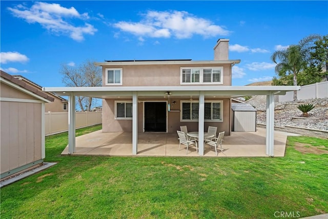 rear view of property with a yard, a fenced backyard, a chimney, stucco siding, and a patio area