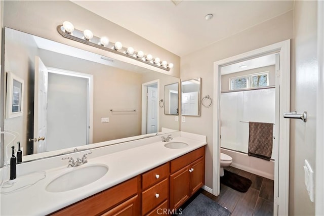 full bathroom with a sink, enclosed tub / shower combo, toilet, and double vanity