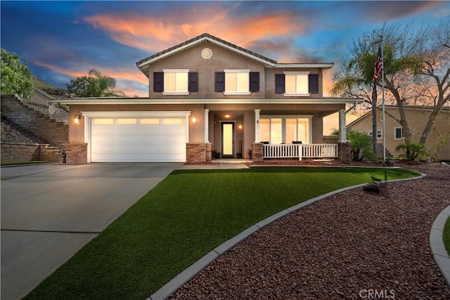 view of front of home with stucco siding, a lawn, driveway, a porch, and a garage