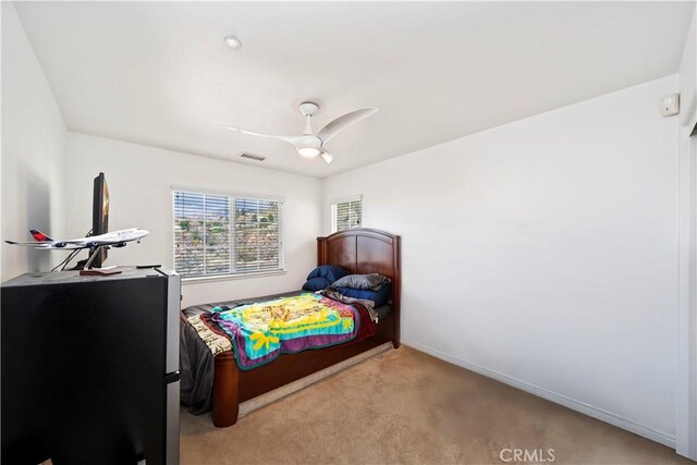 bedroom featuring ceiling fan, baseboards, visible vents, and light carpet