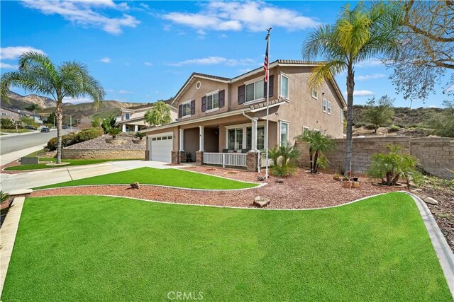 traditional-style house featuring a front lawn, fence, stucco siding, a garage, and driveway