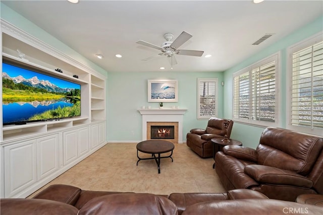 living area featuring built in shelves, a ceiling fan, visible vents, recessed lighting, and a glass covered fireplace