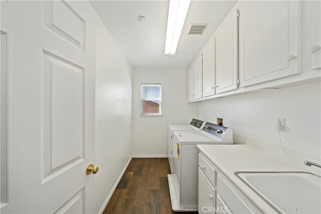 clothes washing area with visible vents, cabinet space, a sink, dark wood-type flooring, and washer and clothes dryer