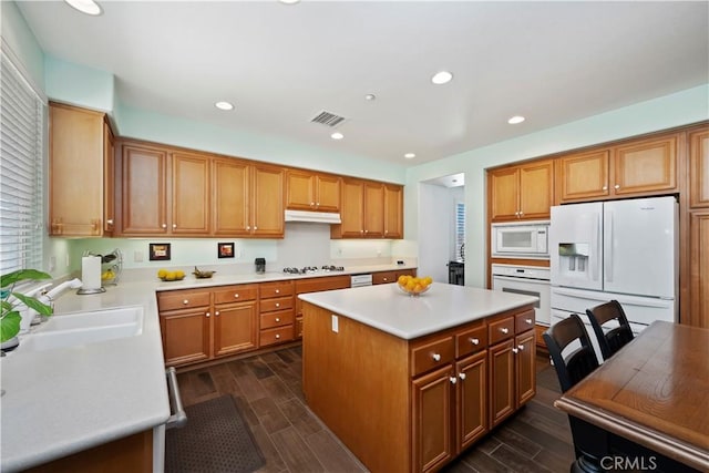 kitchen with under cabinet range hood, visible vents, white appliances, and wood finish floors