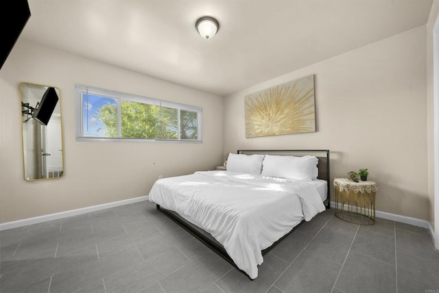 bedroom with dark tile patterned floors and baseboards