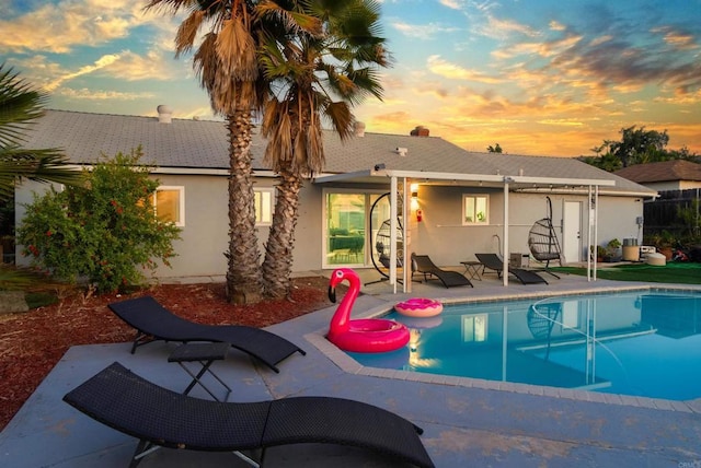 pool at dusk featuring an outdoor pool and a patio