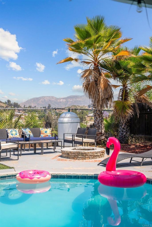 outdoor pool featuring a patio area, fence, and a mountain view