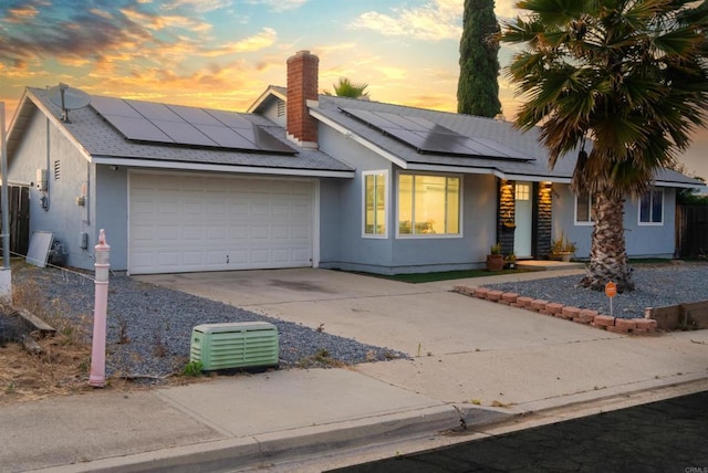 view of front of property featuring concrete driveway, a chimney, roof with shingles, an attached garage, and stucco siding