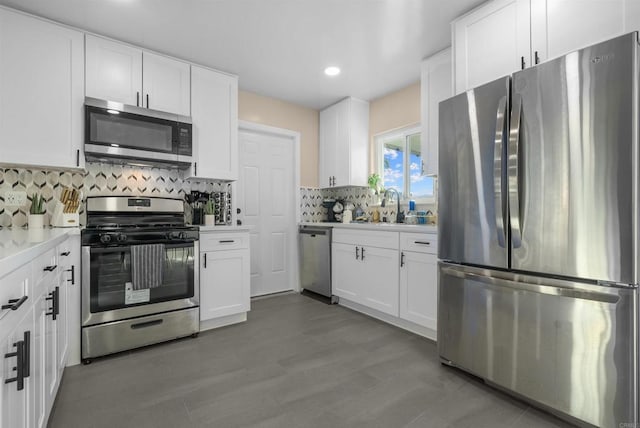 kitchen with tasteful backsplash, light countertops, appliances with stainless steel finishes, white cabinetry, and a sink