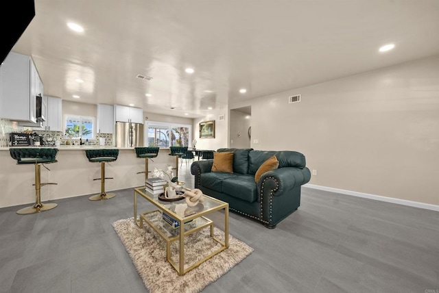 living area featuring baseboards, visible vents, and recessed lighting