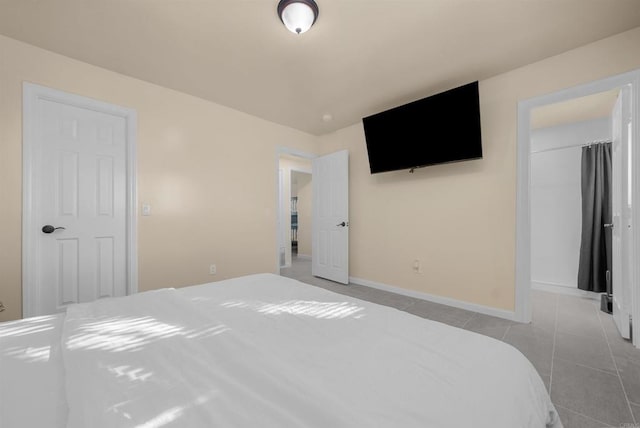 tiled bedroom with baseboards, a walk in closet, and a closet