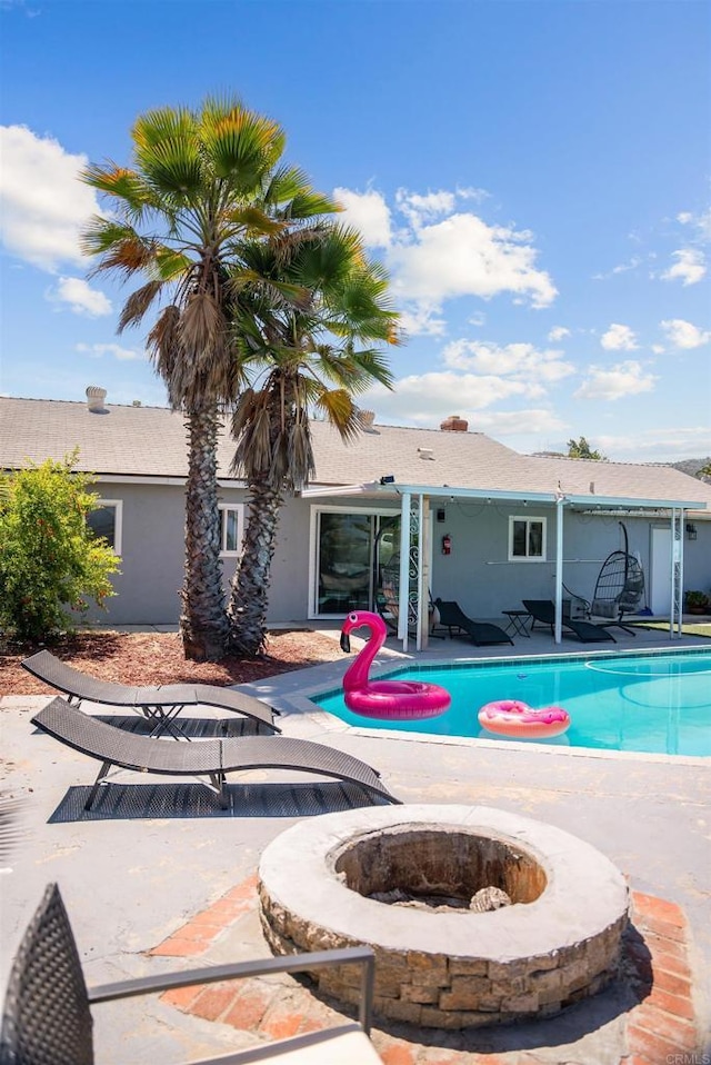 pool with an outdoor fire pit and a patio area