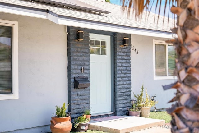 view of exterior entry with stone siding and stucco siding