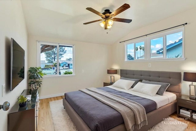 bedroom with light wood finished floors, multiple windows, baseboards, and vaulted ceiling