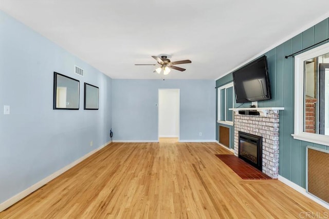 unfurnished living room with visible vents, light wood finished floors, baseboards, a fireplace, and ceiling fan