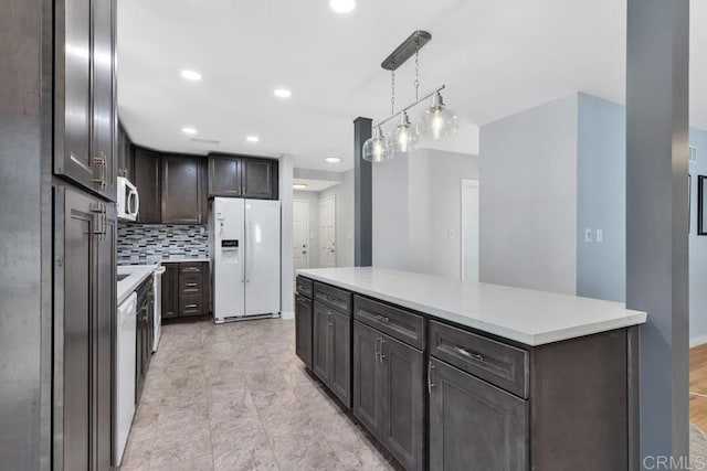 kitchen with backsplash, white appliances, light countertops, dark brown cabinets, and hanging light fixtures