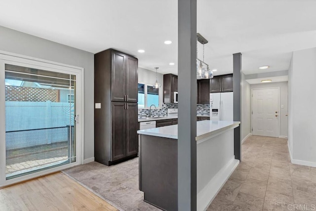 kitchen featuring white appliances, light countertops, backsplash, and dark brown cabinetry